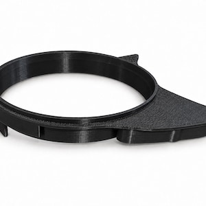 May include: A black, circular, 3D-printed plastic component featuring a smooth, elevated ring structure and an integrated, textured, triangular-shaped extension protruding from one side, with visible layered construction lines throughout the object.
