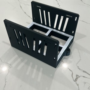 May include: Black plastic storage rack with white accents. The rack has a grid pattern and is designed to hold multiple items.
