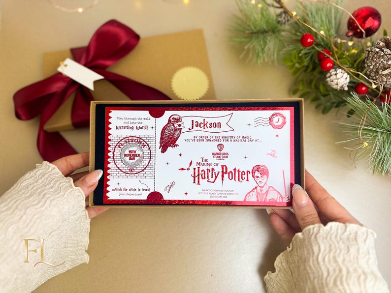 May include: A red and white Harry Potter-themed gift box with a Platform 9 3/4 ticket design. The box is held open, revealing the ticket design, with a red bow and gift box in the background. The text includes "Jackson" and "The Making of Harry Potter".