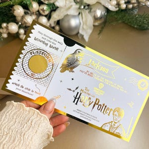 Może przedstawiać: Złoty bilet z napisem "The Making of Harry Potter" i "Platform 9¾". Bilet zawiera ilustrację sowy i imię "Jackson". Tekst zawiera "Merry Christmas Jackson" i "Love Mum xxx".