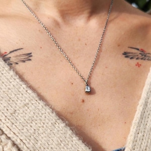 May include: A silver chain necklace with a small, teardrop-shaped pendant.