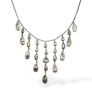 May include: A silver-toned necklace with a delicate chain and multiple teardrop-shaped pendants. The pendants vary in size and hang at different lengths, creating a layered effect. The necklace has a hook clasp.