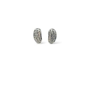 May include: A pair of silver earrings shaped like peanut shells with a textured surface.