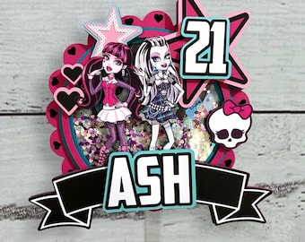 Op de afbeelding: Een kleurrijke taarttopper met twee stripfiguren, het nummer 21 en de naam "ASH". Het ontwerp bevat roze, zwarte en teal accenten, met ster- en hartvormen. Ontworpen voor een verjaardagstaart.