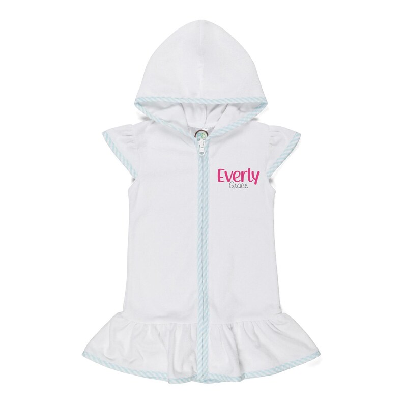 Peut inclure: Combinaison blanche &agrave; capuche pour b&eacute;b&eacute;, avec fermeture &eacute;clair et ourlet &agrave; volants. La combinaison a une bordure bleu clair et le nom "Everly Grace" imprim&eacute; en rose. La combinaison est sans manches et semble &ecirc;tre faite d'un tissu doux.
