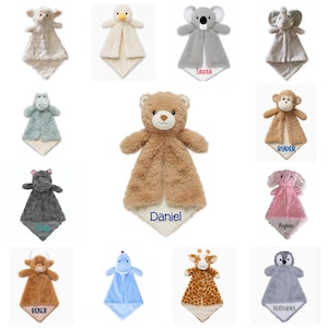 Puede incluir: Una colecci&oacute;n de doce mantitas de seguridad de peluche con varios personajes, incluyendo un oso, koala, elefante, mono y jirafa. Varias mantas est&aacute;n bordadas con nombres como Daniel, Laura, Ryder y Benji.