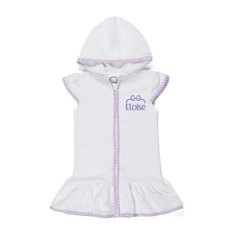 Peut inclure: Peignoir de plage blanc &agrave; capuche avec fermeture &eacute;clair et ourlet &agrave; volants. La bordure est violette et le nom "Eloise" est brod&eacute; en violet. Sans manches.