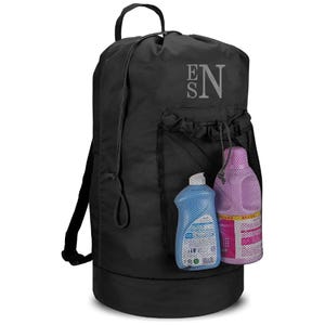 May include: Black drawstring backpack with a mesh pocket holding two detergent bottles. The bag has a top handle and shoulder straps. The letters "EN" are printed on the upper part of the bag.
