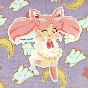 Könnte beinhalten: Ein rosa-weißer Sticker mit einer Comicfigur mit rosa Haaren, einem weißen Kleid und einer roten Schleife. Die Figur zwinkert und hat einen Stern auf der Stirn. Der Sticker trägt den Text "SugarStarlight".