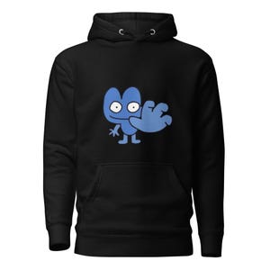 May include: Black hooded sweatshirt featuring a blue cartoon character with large eyes and a waving arm. The character is centered on the front of the sweatshirt. The sweatshirt has a kangaroo pocket and a drawstring hood.