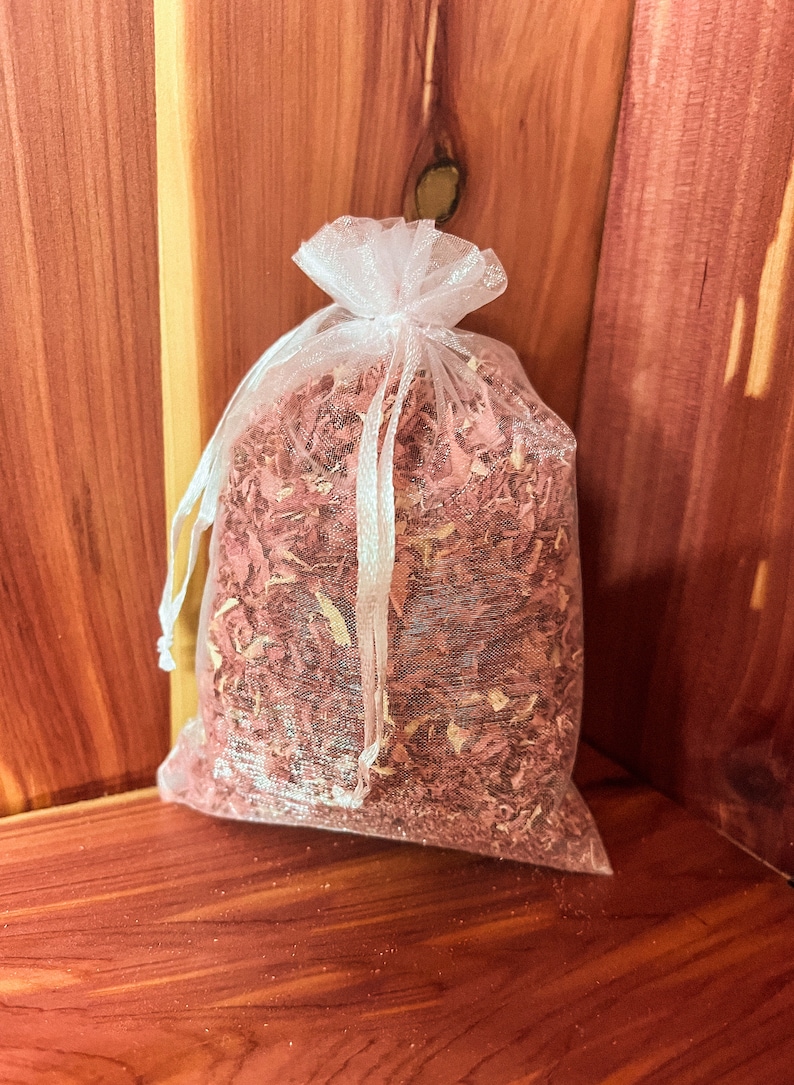 Op de afbeelding: Een witte gaas zak gevuld met cederhouten spaanders. De zak is vastgebonden met een wit lint en ligt op een houten oppervlak.