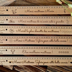 Peut inclure: Cinq règles en bois avec des motifs et des messages différents. Les règles mesurent 30 cm de long et ont une finition en bois brun. Les messages sur les règles incluent "Merci maîtresse Marie", "Merci maîtresse de m'avoir aidé à grandir", "Muriel la plus chouette des maîtresses!", "Merci Maîtresse Sylvie pour cette belle année!" et "Élue meilleure maîtresse!"