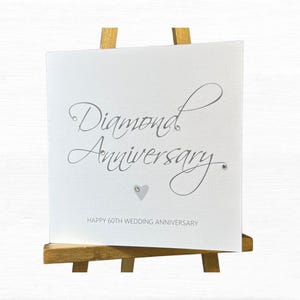 Op de afbeelding: Een vierkante witte wenskaart met de zilverkleurige cursieve tekst Diamond Anniversary, versierd met kleine doorzichtige kristallen en een klein hartje. Daaronder staat de tekst HAPPY 60TH WEDDING ANNIVERSARY in hoofdletters.