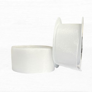 Op de afbeelding: Twee witte lintrollen tegen een witte achtergrond. Eén rol ligt op zijn kant, de andere staat rechtop en toont de rand van het lint. Het lint lijkt van satijn of een vergelijkbaar materiaal te zijn, geschikt voor knutselen en cadeauverpakkingen.