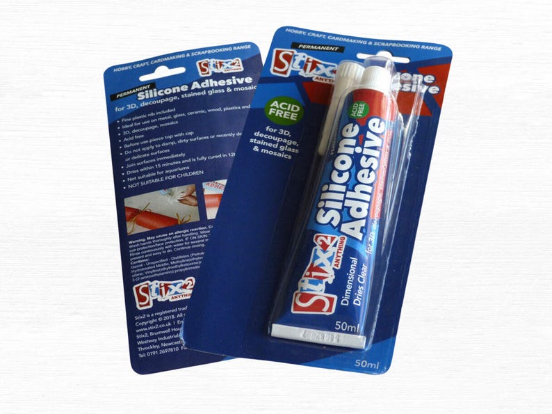 May include: Two packages of Stix2 Silicone Adhesive, a permanent, acid-free adhesive for 3D decoupage, stained glass, and mosaics. The tube contains 50ml of clear adhesive. The packaging is blue and white.