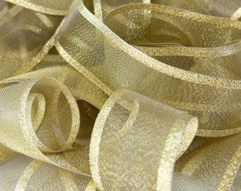 May include: Gold sheer ribbon with a metallic sheen. The ribbon has a thin gold stripe along each edge.