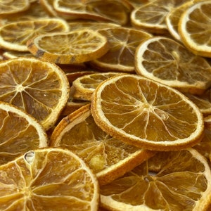 May include: A close-up of a pile of dried orange slices. The slices are a deep orange color and have a slightly translucent appearance. They are arranged in a random pattern, with some overlapping.