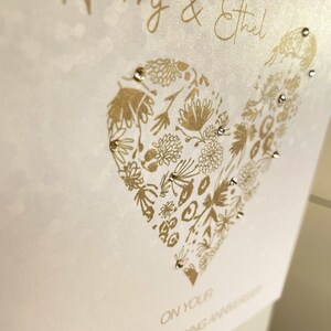 Golden Wedding Anniversary card printed on sequin-effect pearlescent card, featuring a floral gold heart design and personalised names, hand finished with sparkling gold diamantes.