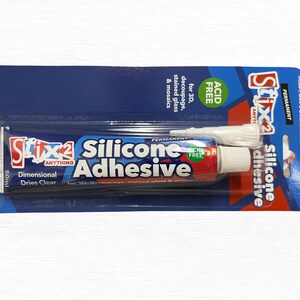 May include: A tube of Stix2 Silicone Adhesive, 50ml, on a blue and white card. The tube is red, white, and blue with the words "Silicone Adhesive" prominently displayed. The packaging indicates it's acid-free and suitable for 3D decoupage, stained glass, and mosaics.