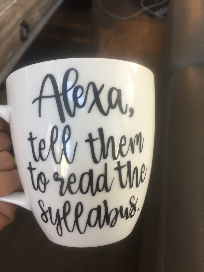 Op de afbeelding: Een witte keramische mok met zwarte tekst die "Alexa, zeg tegen ze dat ze de syllabus moeten lezen." zegt.