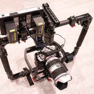 Puede incluir: Un equipo de c&aacute;mara profesional con una c&aacute;mara montada, un monitor y paquetes de bater&iacute;as. El equipo es negro con un monitor plateado y una lente grande. Tiene asas y varios puntos de montaje para accesorios. La lente de la c&aacute;mara es blanca y negra.