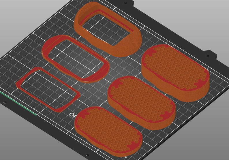 May include: Five 3D printed objects on a black grid surface. Four of the objects are rectangular frames with rounded corners. One object is a solid, oval-shaped object with a honeycomb pattern.