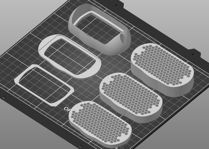 May include: Five 3D printed objects on a black grid surface. Two are rectangular frames, one is a rounded frame, and two are oval-shaped with a honeycomb pattern.