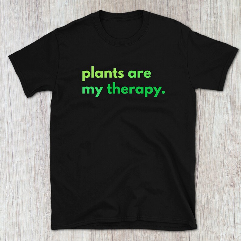 Puede incluir: Camiseta negra con el texto "plants are my therapy." en verde.