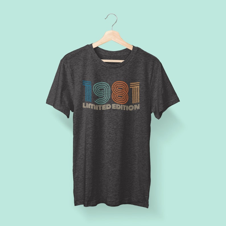 May include: A dark grey t-shirt with a vintage-style graphic of the year 1981 in colorful stripes. The text "LIMITED EDITION" is printed below the year.