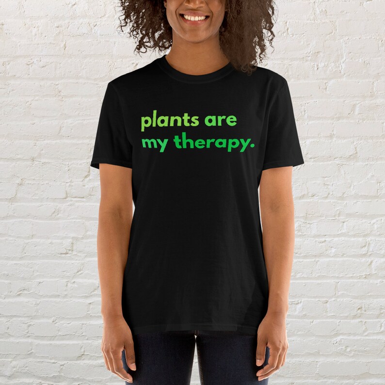 Puede incluir: Una camiseta negra con el texto "plants are my therapy." en verde.