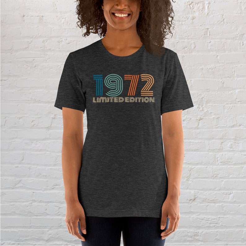 May include: A dark heather grey t-shirt with a vintage-style graphic of the year 1972 in rainbow colors. The text "Limited Edition" is printed below the year.