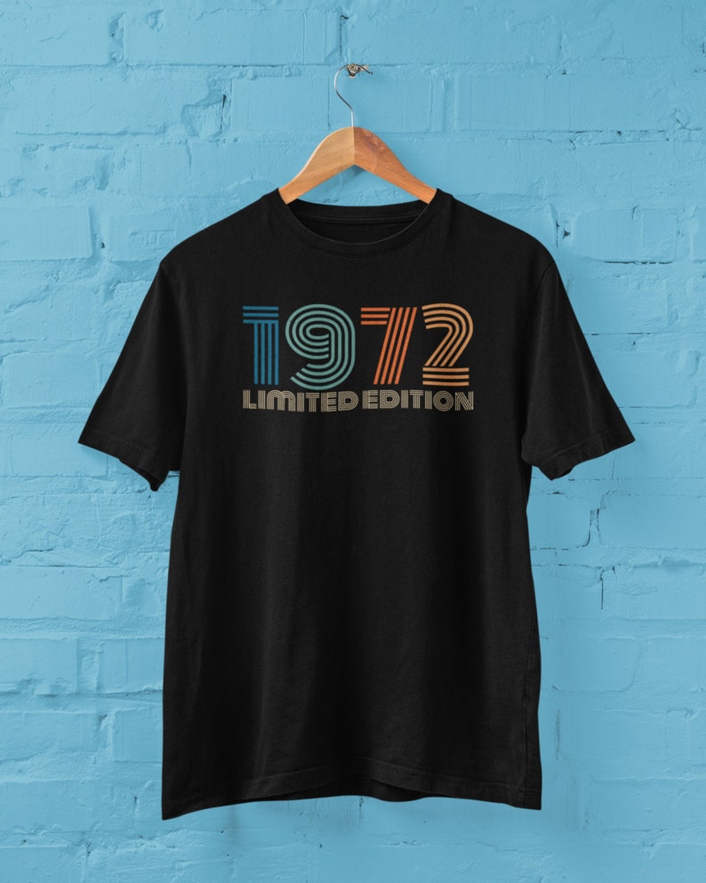 May include: Black t-shirt with a vintage-style graphic of the year 1972 in orange, blue, and yellow stripes. The text "LIMITED EDITION" is printed below the year.