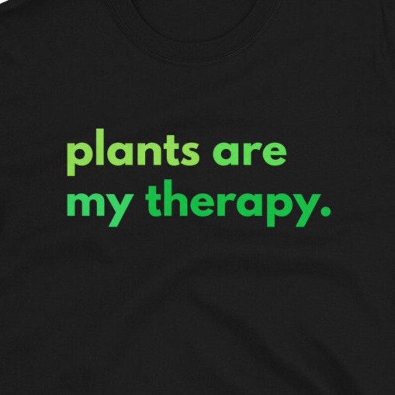 Puede incluir: Camiseta negra con texto verde que dice "las plantas son mi terapia."