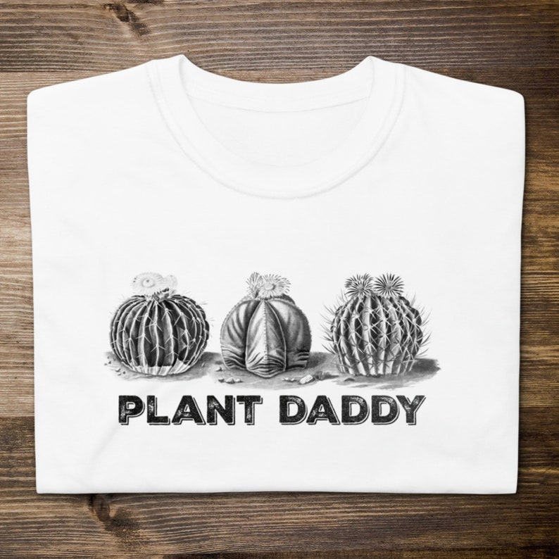 May include: White t-shirt with a black and white illustration of three cacti and the text "PLANT DADDY" printed on the front.