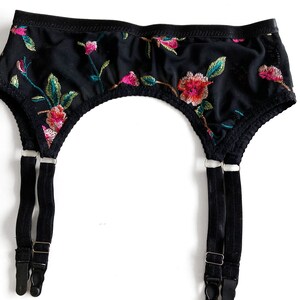 May include: Black garter belt with floral embroidery and adjustable straps. The straps have metal clips.