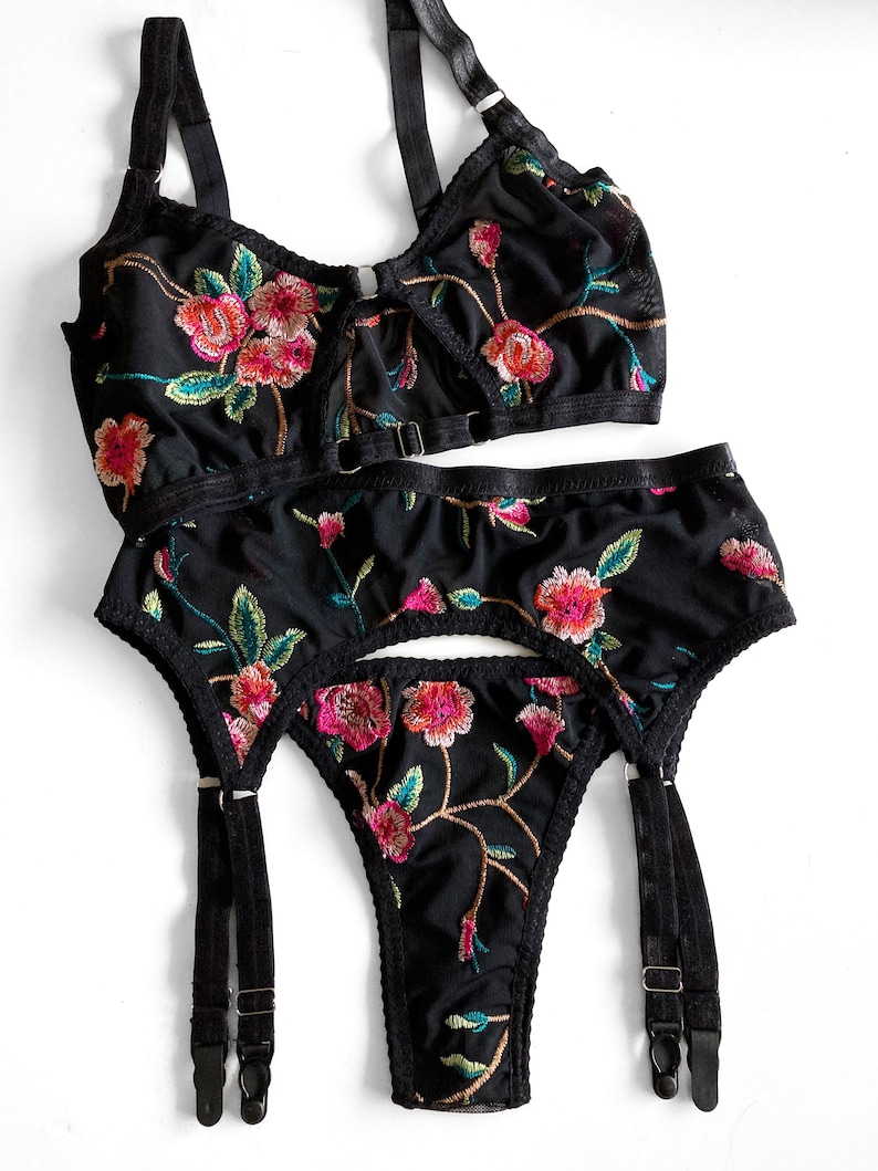 May include: Black lingerie set with floral embroidery. The set includes a bra with adjustable straps and a garter belt with adjustable straps.