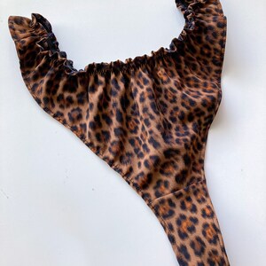 May include: Leopard print underwear with a ruffled top and a thong style bottom.