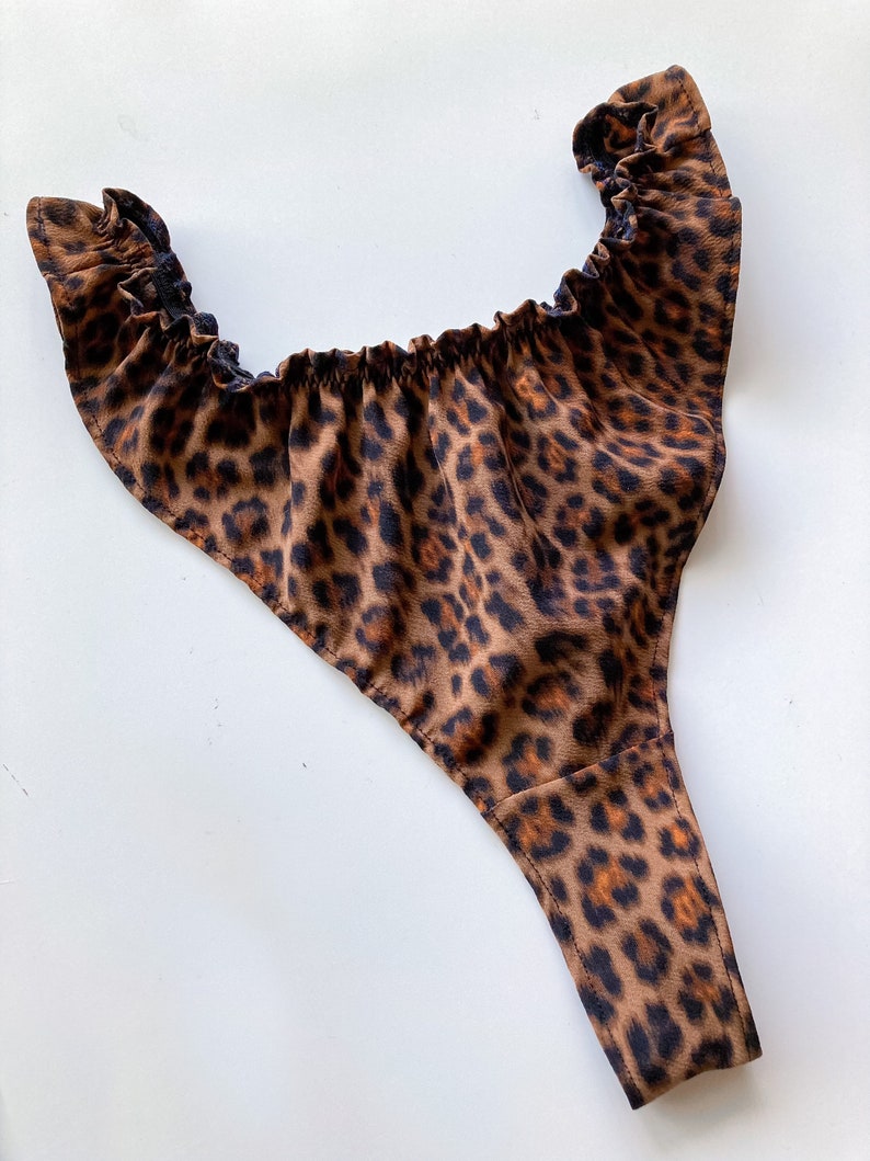 May include: Leopard print underwear with a ruffled top and a thong style bottom.