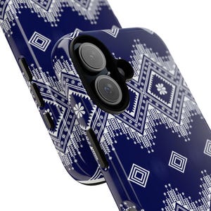 May include: A close-up of a navy blue phone case with a white geometric pattern. The case features a repeating design of squares, diamonds, and floral motifs. The phone case has a glossy finish and a camera lens cutout.