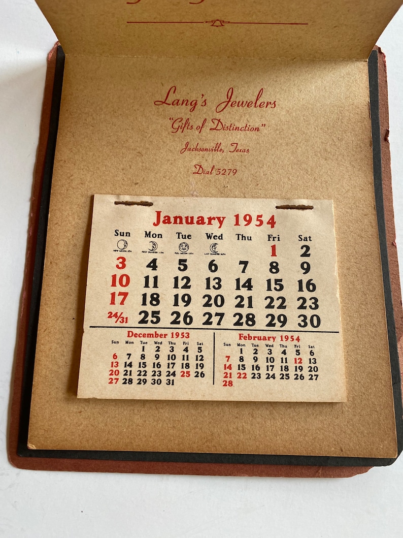 May include: Vintage pocket calendar from Lang's Jewelers, Jacksonville, Texas, featuring the January 1954 calendar page. The calendar also shows December 1953 and February 1954. The calendar is in a brown leather-like cover.