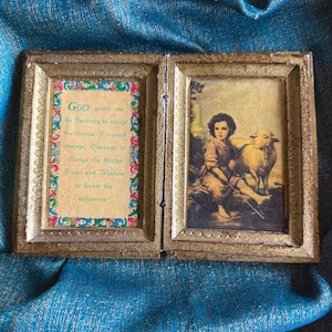 May include: A vintage, hinged picture frame with two panels. One panel features the text "GOD grant me the Serenity to accept the things I cannot change..." The other panel shows a child with a lamb. The frame has a gold finish.