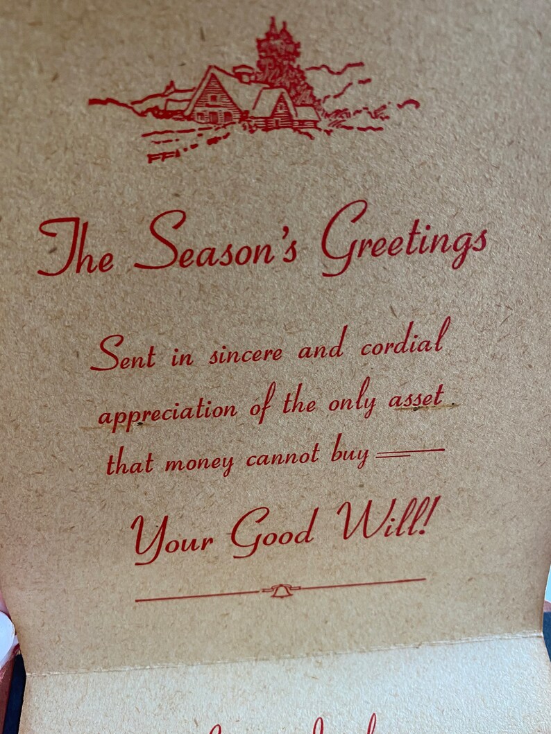 May include: A vintage greeting card with the text "The Season's Greetings" in red script. The card features a red illustration of a cabin in the mountains. The message continues with "Sent in sincere and cordial appreciation of the only asset that money cannot buy - Your Good Will!"