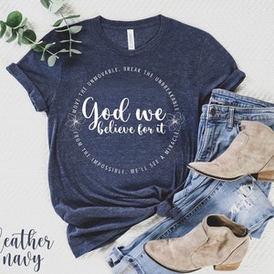 May include: A heather navy blue t-shirt with a white circle graphic that says "Move the Unmovable, Break the Unbreakable. God we believe for it. From the Impossible, We'll see a Miracle."