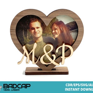 May include: A wooden heart-shaped picture frame with a stand. The frame has a cutout in the shape of the letters "M&P". A photo of a couple is visible in the frame.