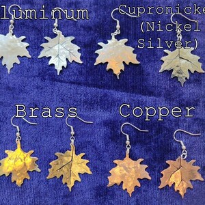 Peut inclure: Un ensemble de huit boucles d'oreilles en forme de feuille d'érable en différents métaux, dont l'aluminium, le laiton, le cuivre et le cupronickel (argent nickelé). Les boucles d'oreilles sont présentées sur un fond de velours bleu.