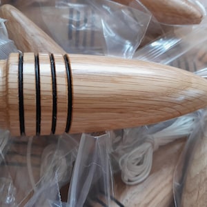 May include: A wooden honey dipper with a light brown finish. The dipper has a rounded handle and a grooved head with black accents. White string is attached to the dipper. The dippers are in clear plastic bags.