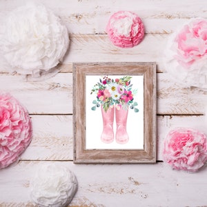 K&ouml;nnte beinhalten: Ein gerahmter Druck von rosa Gummistiefeln mit einem Strau&szlig; rosa, wei&szlig;er und lila Blumen. Der Hintergrund ist wei&szlig;.