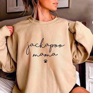 May include: Tan sweatshirt with the text "jackapoo mama" and a paw print.