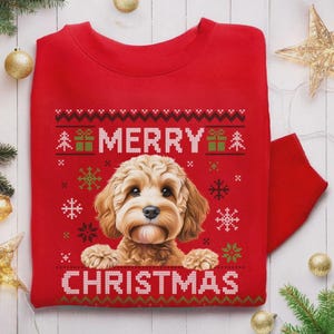 May include: A bright red crewneck sweatshirt featuring a central illustration of a light brown, fluffy dog. The design includes the white text MERRY CHRISTMAS, surrounded by green and white patterns of snowflakes, small trees, and gift boxes.