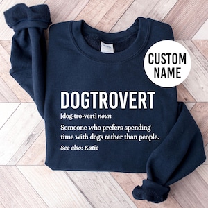 May include: Navy blue sweatshirt with the text "DOGTROVERT [dog-tro-vert] noun Someone who prefers spending time with dogs rather than people. See also: Katie" printed in white.